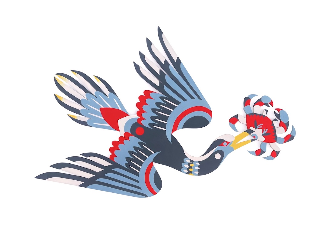 A stylized illustration of a bird with blue, red, white, and yellow patterns, flying while holding a decorative red and white object in its beak, against a plain white background.